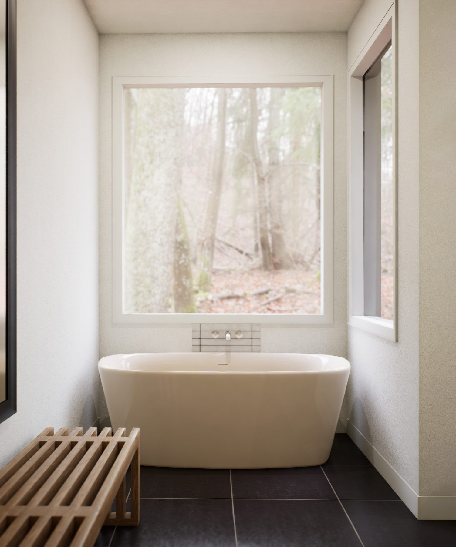 Freestanding tub in front of a forest window